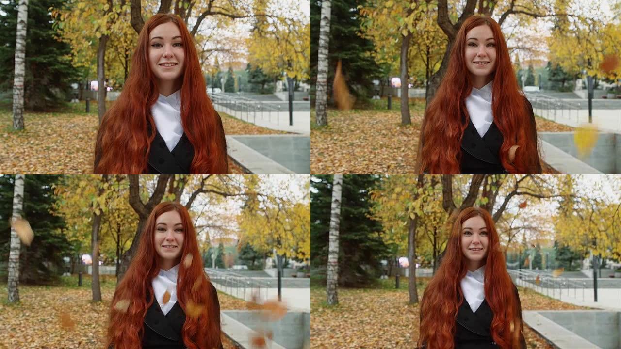 一个留着飘红头发的女孩站在公园落叶下。