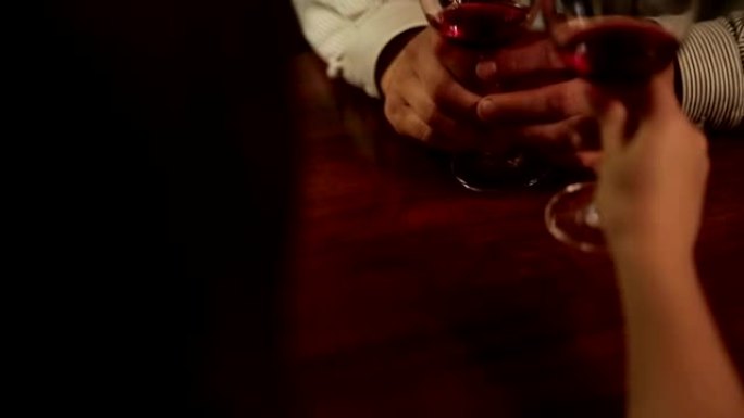 亲密的年轻情侣的手碰杯红酒。餐厅里的浪漫晚餐