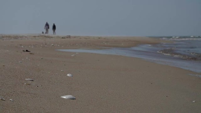 无法识别的人剪影在沙滩上行走，慢动作