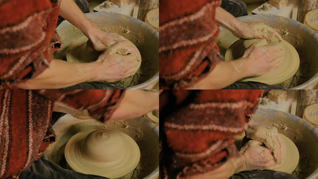 职业男陶工在陶工的轮子上使用粘土