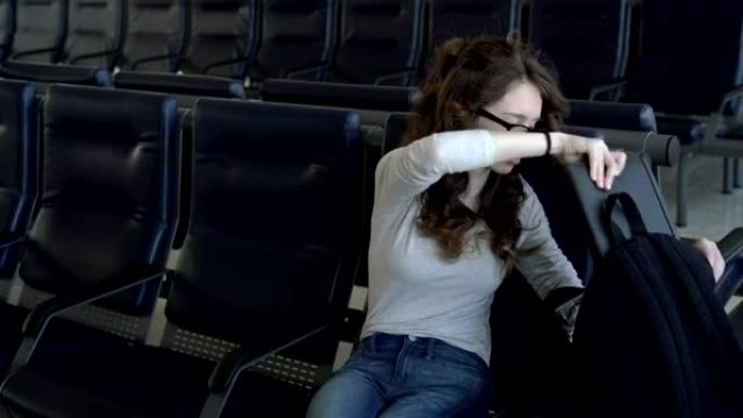 十几岁的女孩在机场候机室等待航班时，将自己的东西重新包装在背包中