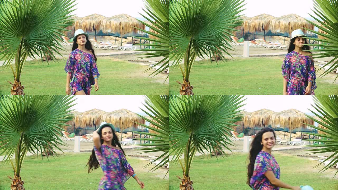夏天，年轻的晒黑的长发女子在热带棕榈树之间跳舞