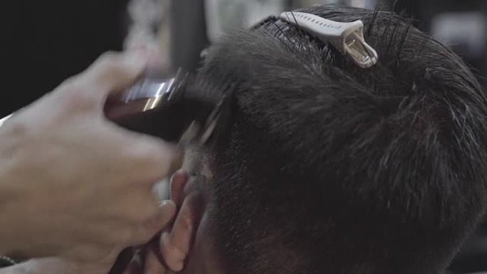 理发师用理发机器剪掉客户的头发。理发男理发店