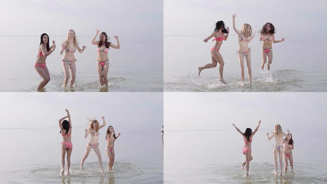 三个十几岁的女孩在海滩日落时在水中跳舞。慢动作
