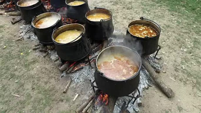木火上的传统大锅。炖肉由肉，辣椒，西红柿制成。加水。一个男人正在用木勺在锅里搅拌肉