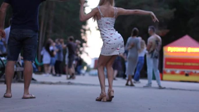 女性双腿跳舞萨尔萨舞。人们在晚上的城市公园跳舞。性感萨尔萨舞运动。选择性聚焦。