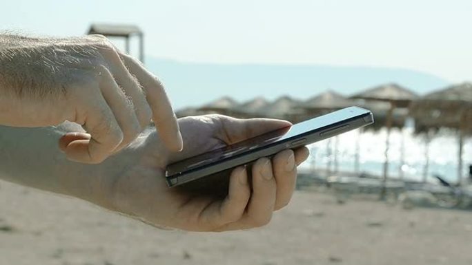 在海滩上使用智能手机的特写镜头