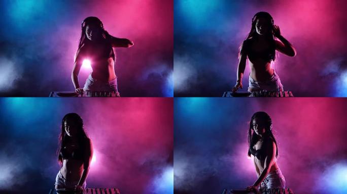 女孩DJ跳舞在她五彩缤纷的灯光和烟雾后面发展她的头发。剪影