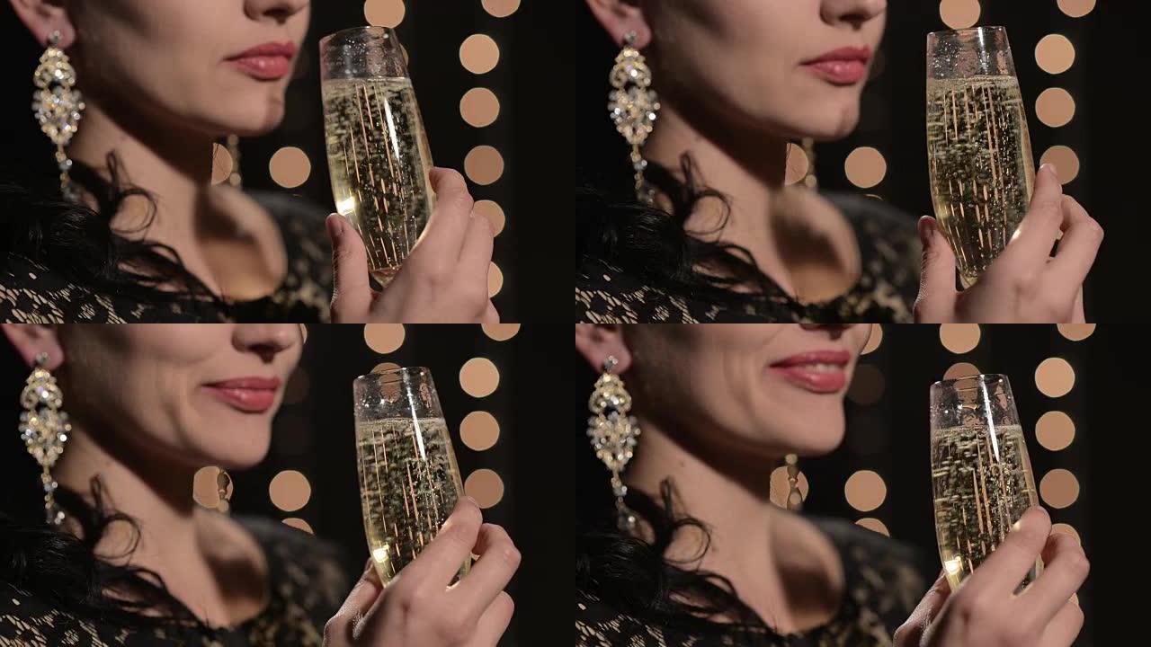 女人晚上在庆祝灯的背景下从杯子里喝香槟