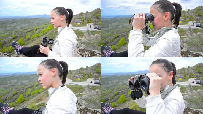 年轻女孩用双筒望远镜在山顶徒步旅行