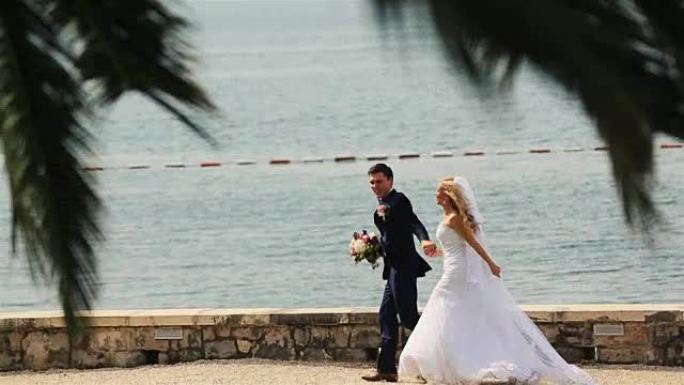幸福的婚礼情侣在黑山、布德瓦的海滩上奔跑和大笑，享受风景