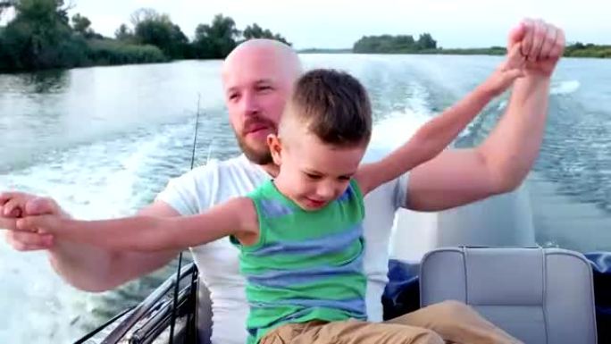 周末和孩子在一起的好爸爸，父子俩在一起度过时光，在快艇上快速行驶时做出情感反应
