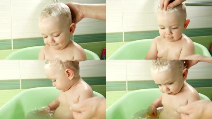 快乐的宝宝洗澡玩泡沫泡泡。妈妈洗小男孩。浴缸里的小孩。带着玩具在浴室里微笑的孩子。父母和孩子玩水