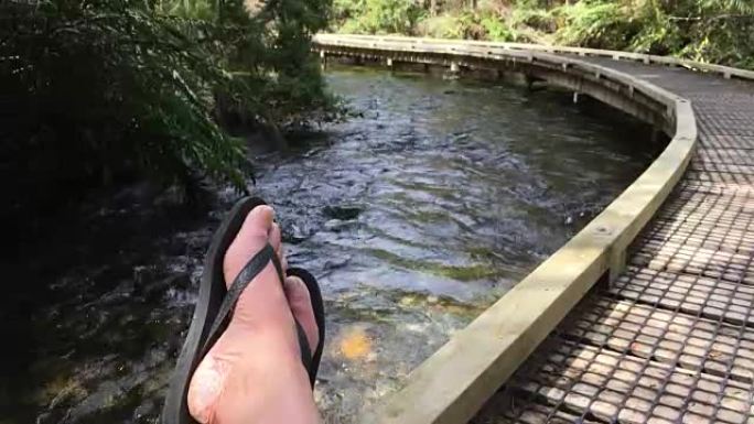 夏天，Jandal自拍脚在大自然的一条河上的木板路上放松