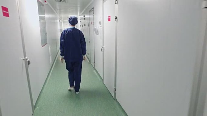 穿着防护服的女医生在医院走廊行走的背景图