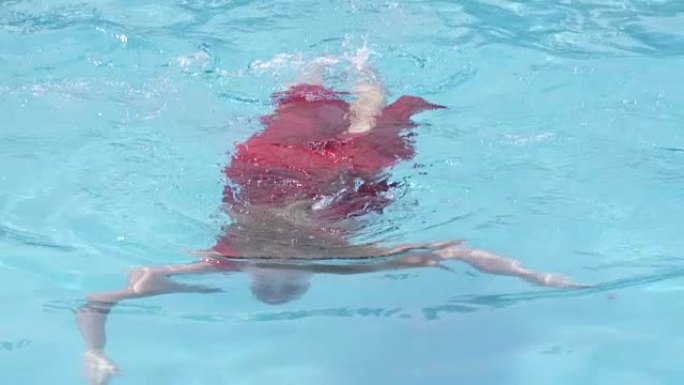 穿着红色长裙的女孩在水下游泳的游泳池水面