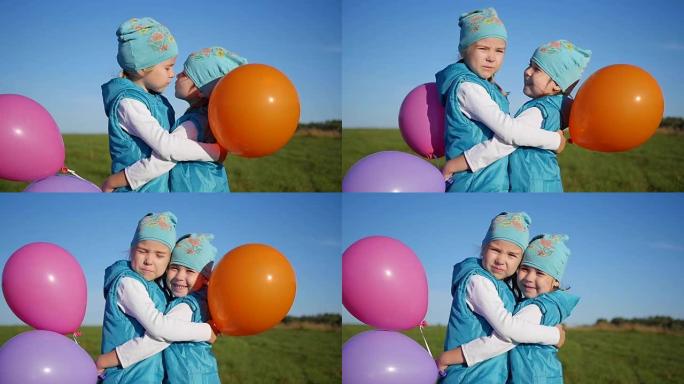 两个双胞胎姐妹拥抱和亲吻。孩子们拿着气球