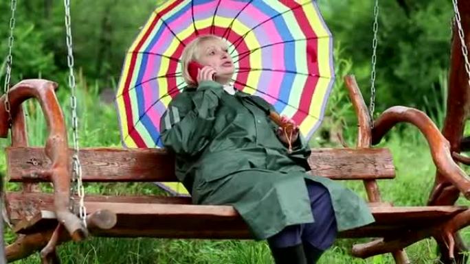 带着雨伞的女人坐在秋千上，用手机交流