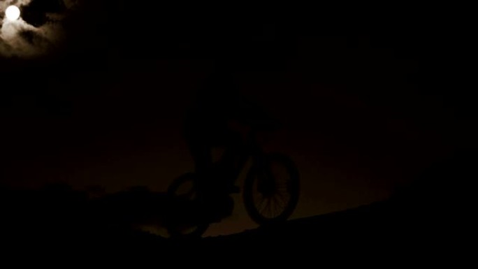 骑自行车的人在月光下经过艰苦的骑行后返回家中