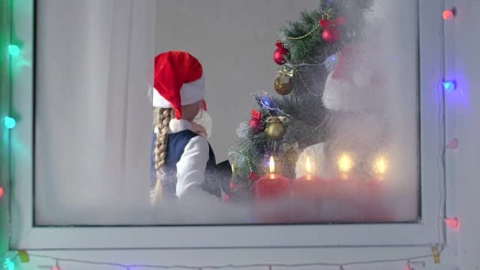 孩子们在家通过窗户装饰圣诞树