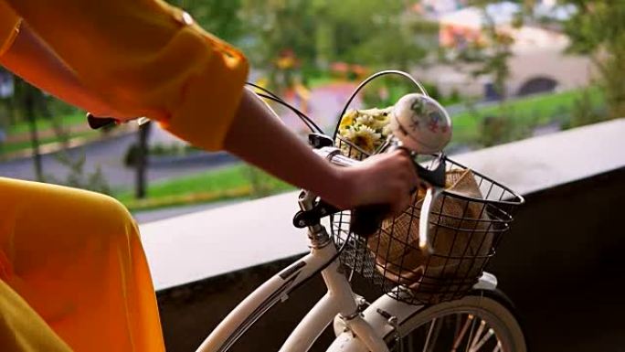 城市自行车车把的特写视图，带有铃铛，篮子和鲜花。一早骑城市自行车的面目全非的女人。斯蒂安卡姆开枪。慢