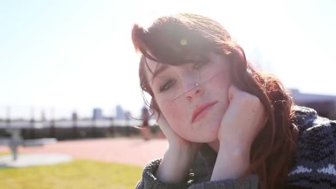 美丽的红发女郎坐在公园里看起来很庄重
