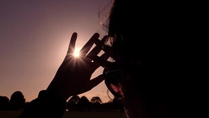 年轻女子用手保护眼睛看着太阳