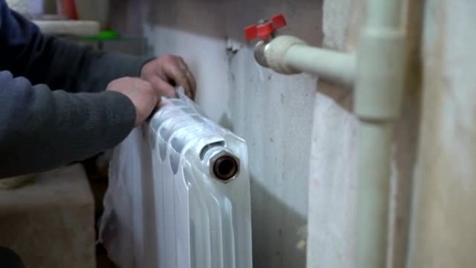 用新的替换旧的热水散热器。水管工手在工作的特写镜头。