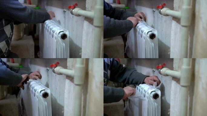 用新的替换旧的热水散热器。水管工手在工作的特写镜头。