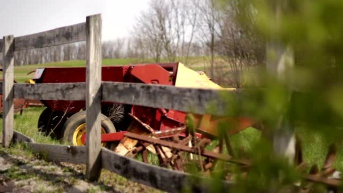 通用的旧农场干草保释机车坐在农田乡村的篱笆附近