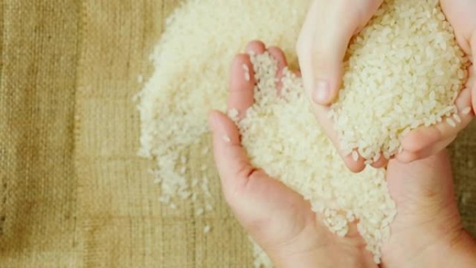 双手成年妇女拿着一粒米，在他们身上像孩子的手一样拿着米