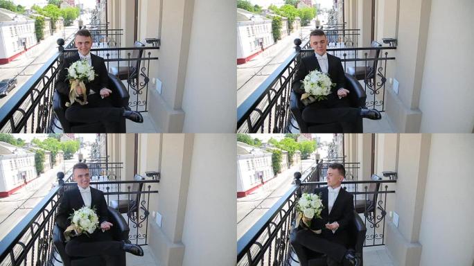 新郎拿着婚礼花束坐在阳台上。时间流逝