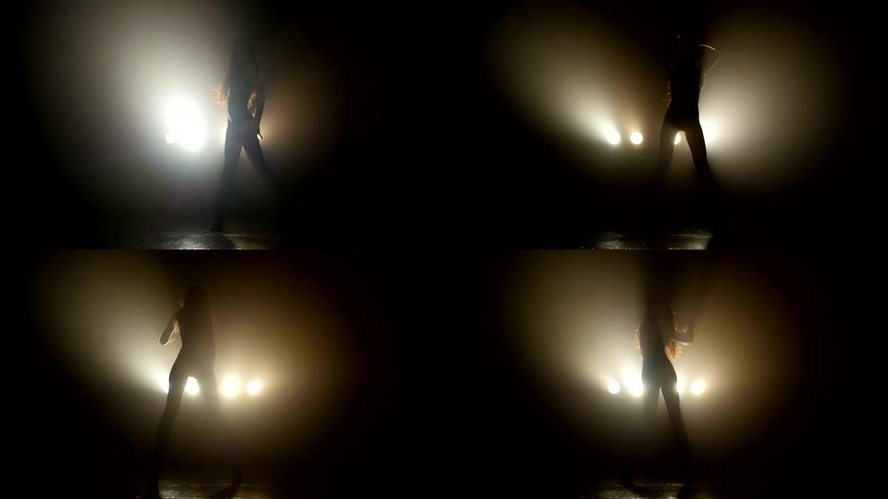 一个女孩在背景灯上跳舞的剪影。慢动作