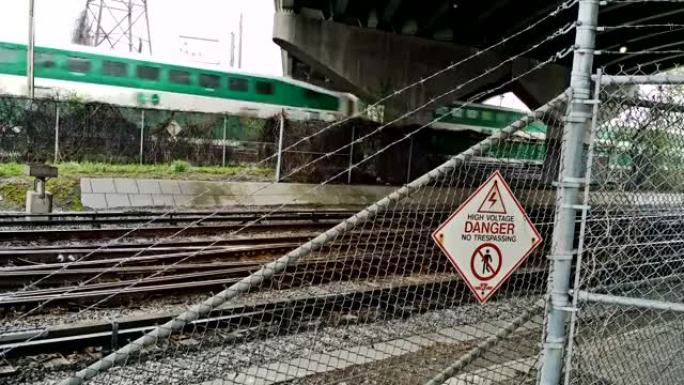 通勤和地铁列车在带有危险标志的桥下通过。