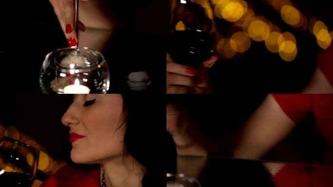 穿着红色连衣裙的美丽黑发女郎在镜子桌上玩蜡烛和融化的冰块，喝红酒