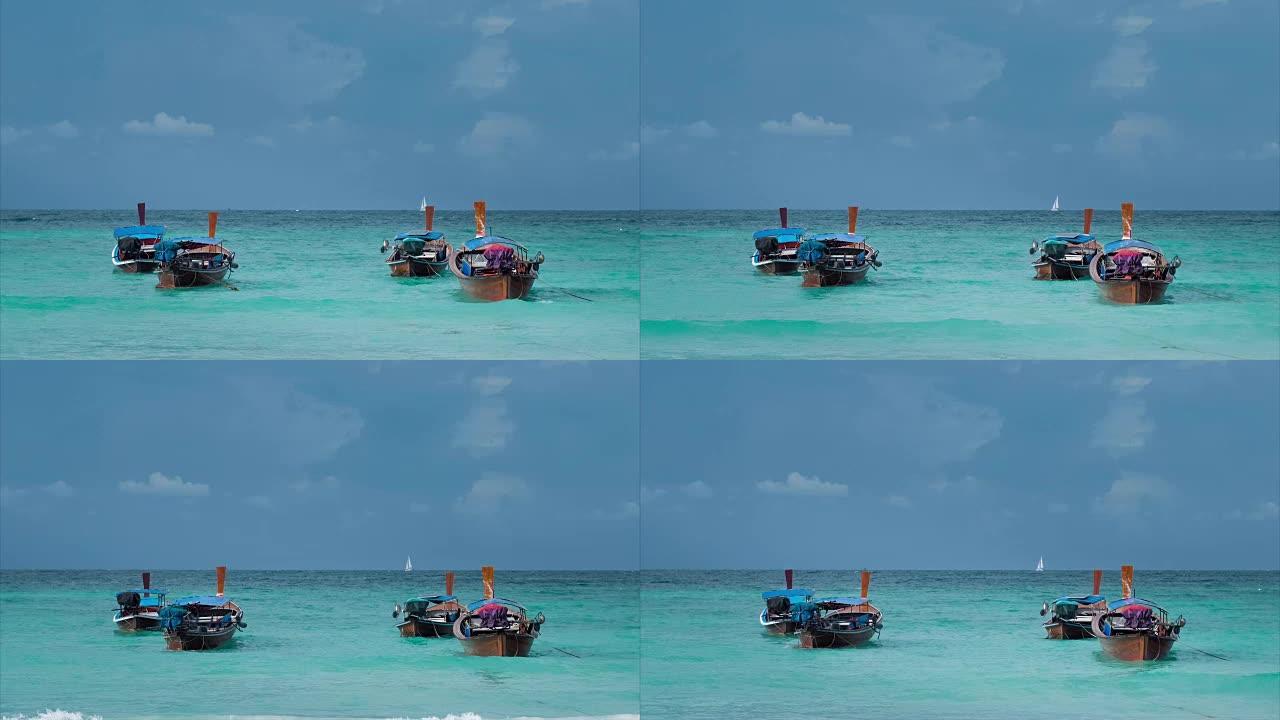 蓝色波浪中摆动的四艘长尾船，地平线上的白色帆船，泰国Koh Lipe