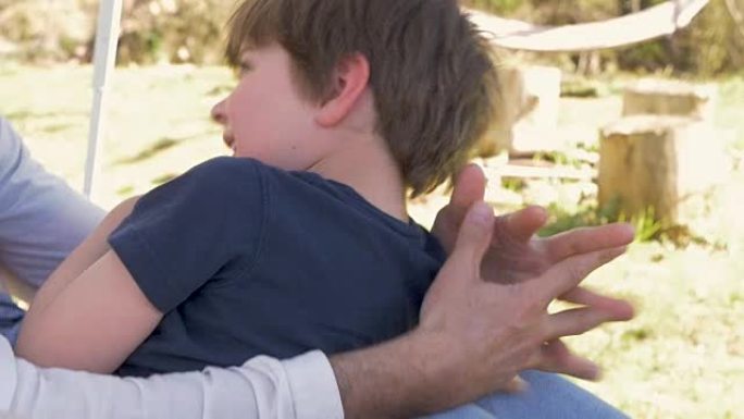 一位父亲在将他的小儿子抱在腿上时挠痒痒