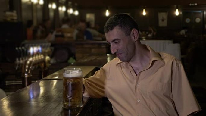 可怜的沮丧的人在酒吧里独自喝啤酒