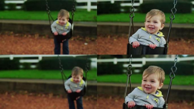 可爱的小男孩在慢动作的秋千上，脸上挂着灿烂的笑容