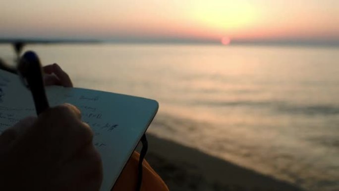 女人在日落时坐在海边做笔记