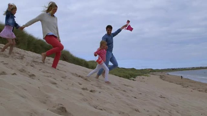 家庭在海滩度假中的慢动作顺序一起穿过沙丘