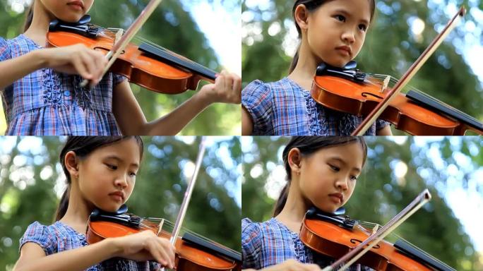 亚洲小女孩在公园拉小提琴