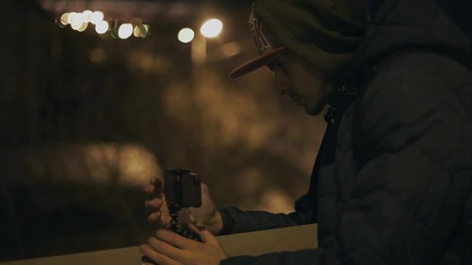 男子站在三脚架上的智能手机上拍照