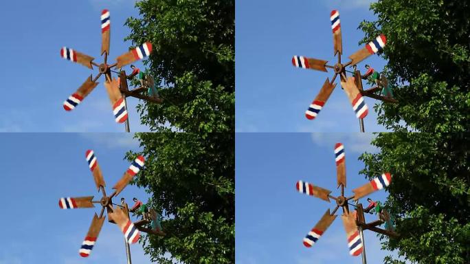 木质花园风力涡轮机在蓝天和树木背景下从花园中的风旋转