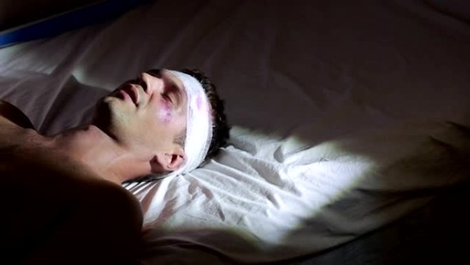 头部受伤的人躺在床上。包扎的头。他脸上有瘀伤。