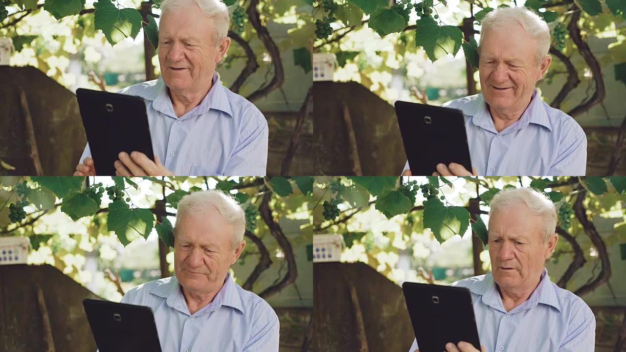 快乐的老年人在花园里使用平板电脑。全高清