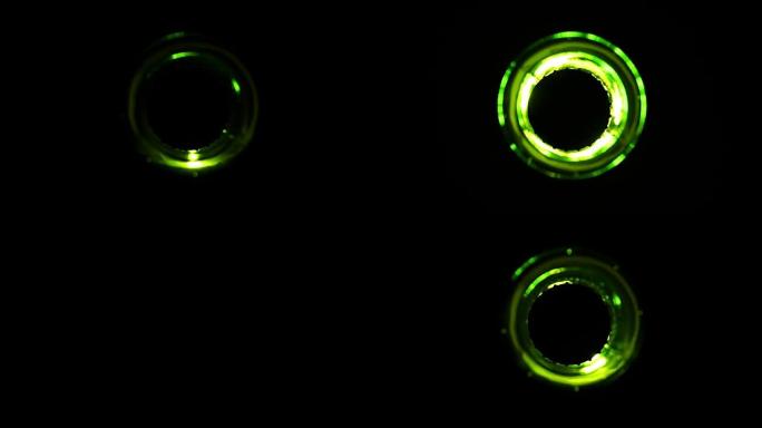 俯视图: 绿色啤酒瓶在黑色背景上快速点亮和熄灭
