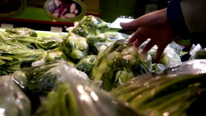 中国超市内男子选择蔬菜的运动