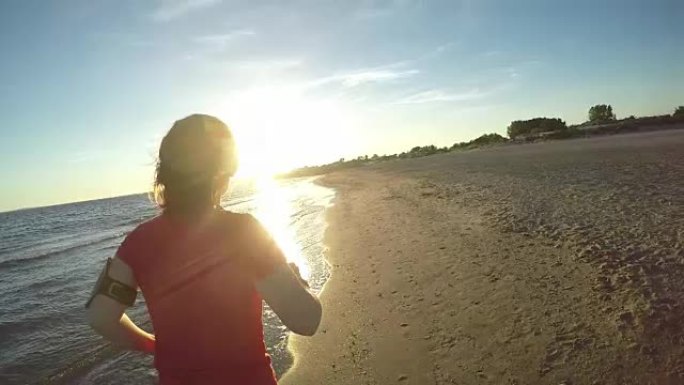 女孩在日落时沿着海滩奔跑
