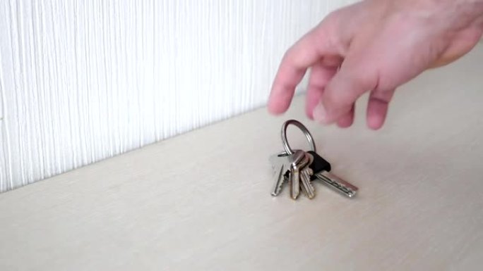 男人的手从桌子上拿房子的钥匙